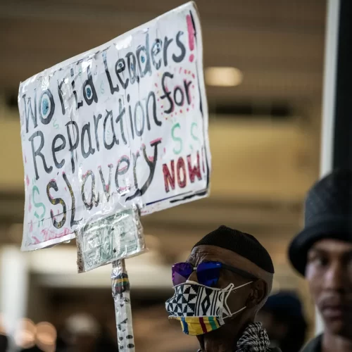Walter Forster, a Los Angeles resident, holds a sign that advocates for financial compensation during the California Reparations Task Force meeting that was held at the California Science Center in Los Angeles on Sept. 23, 2022. Photo by Pablo Unzueta for CalMatters